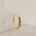 The Flower Bar Ring in Rose Gold features an engraved daisy and bud, standing upright against a textured light surface—a perfect botanical jewelry piece for nature lovers.