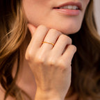 A woman with loose wavy hair touches her chin, wearing the elegant Eleanor Baguette Diamond Ring on her finger.