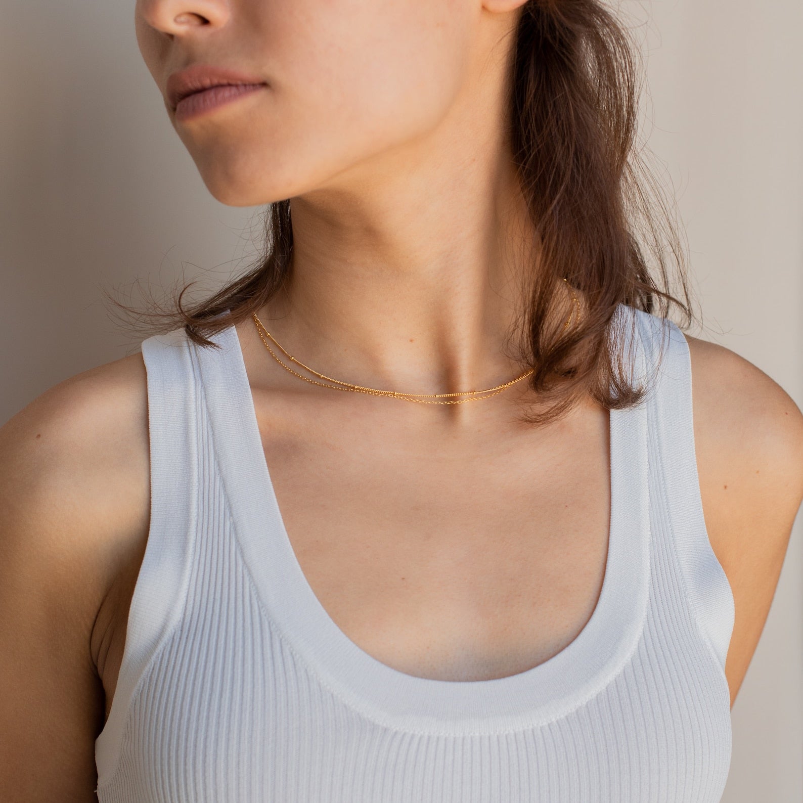 Woman wearing a white ribbed tank top and the Beaded Duo Chain Necklace, shown from shoulders to chin.
