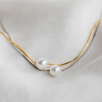 The Kennedy Pearl Necklace, available in gold and silver, is elegantly displayed on soft white fabric—perfect minimalist jewelry for any wedding collection.