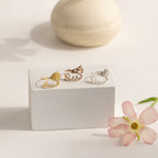 Four Flower Name Rings displayed on a white block, with a pink flower and ceramic accent—perfect as personalized flower jewelry or a custom Birth Flower Name Ring, making them an ideal gift for mom.