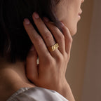 A person touches their neck while wearing the Bold Name Ring, personalized with the name Emily engraved on their finger.