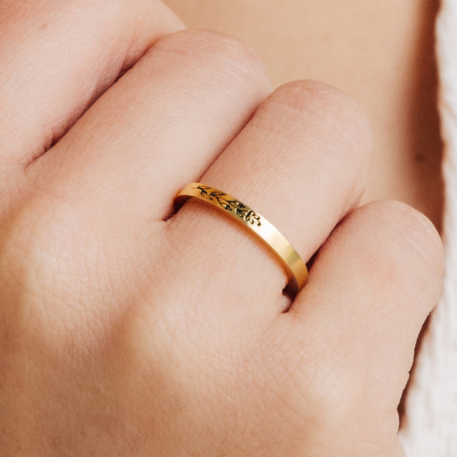 The Stacking Flower Band, a delicate gold ring with a floral motif and slender band, is perfect for botanical jewelry lovers and beautifully adorns any finger.