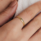 A Skinny Flower Ring with engraved detail adorns a hand with neatly manicured nails, adding a touch of botanical elegance.