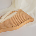 The Nanala Diamond Flower Necklace is displayed elegantly on a wavy wooden board, paired with a gold bracelet, and accented with fabric and dried grass for added charm.