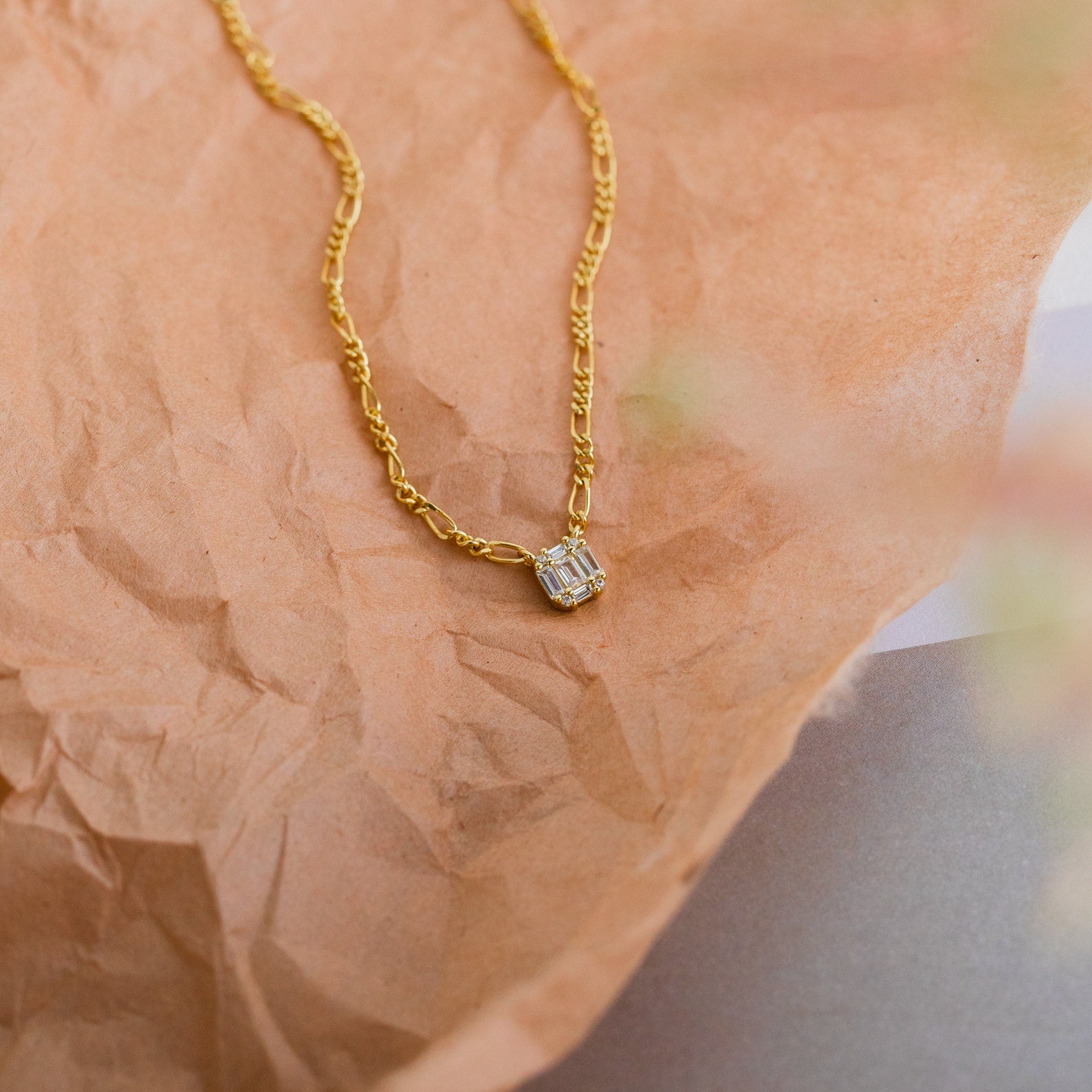 Square Diamond Figaro Necklace featuring a square pendant adorned with shimmering baguette diamonds, shown on crumpled brown paper.