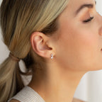With her eyes closed in profile, a woman with blonde hair in a low ponytail wears the Aria Diamond Drop Studs.