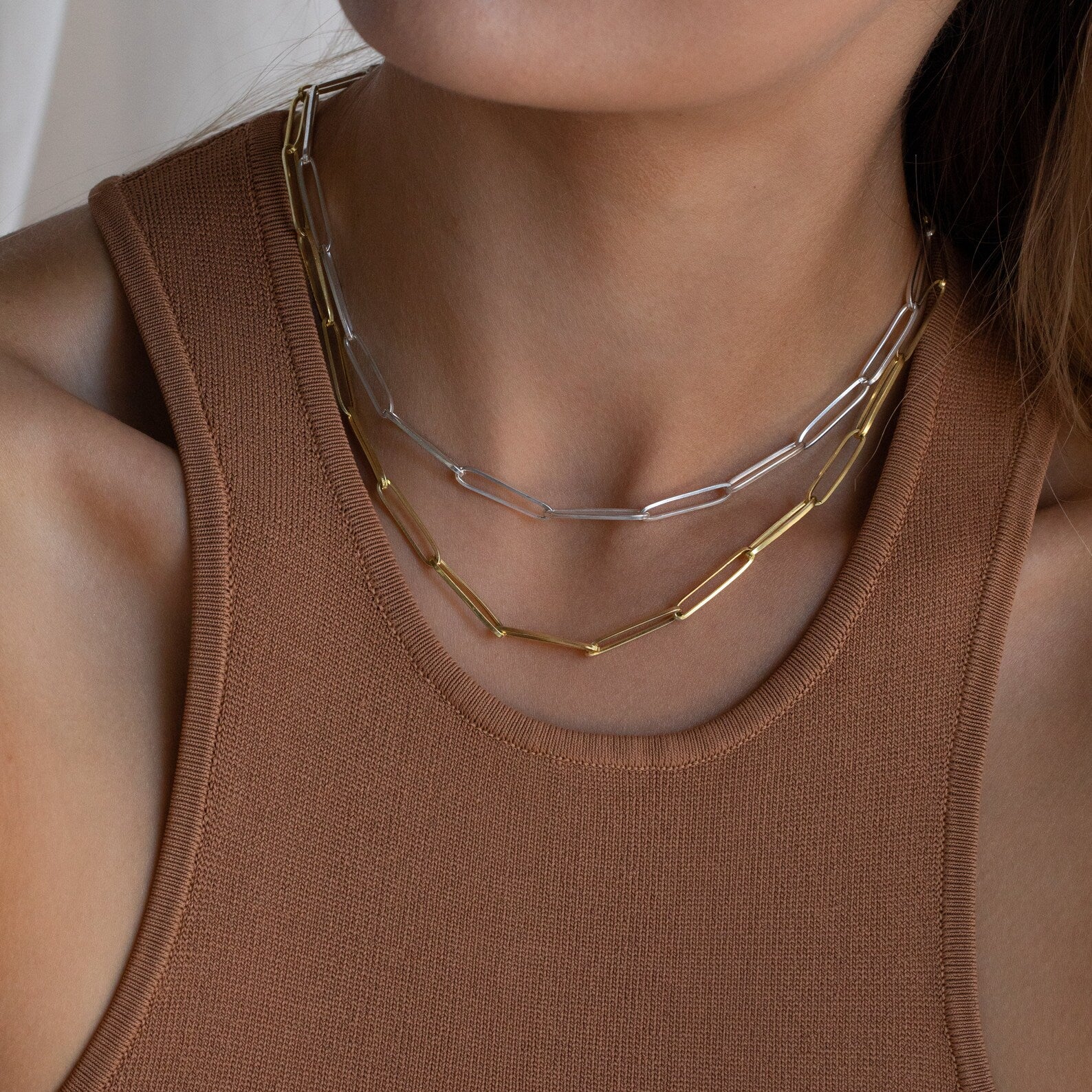 Woman wearing a brown tank top with layered statement necklaces, including the Custom Link Chain Necklace in bold gold and silver tones.