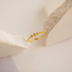 The Jasmine Beaded Diamond Ring features two small star-shaped charms in gold, ideal for stacking, and is showcased on a neutral, textured background.