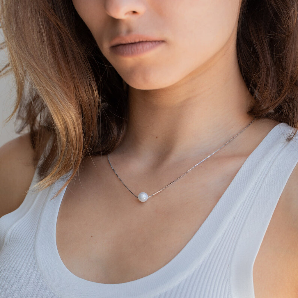 Woman wearing a white tank top and the Kennedy Pearl Necklace, a delicate pendant that's perfect for minimalist jewelry lovers.