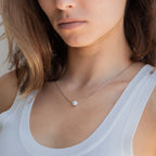 Woman wearing a white tank top and the Kennedy Pearl Necklace, a delicate pendant that's perfect for minimalist jewelry lovers.