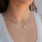 A woman wearing a white top and the Kennedy Pearl Necklace, ideal for fans of minimalist jewelry.