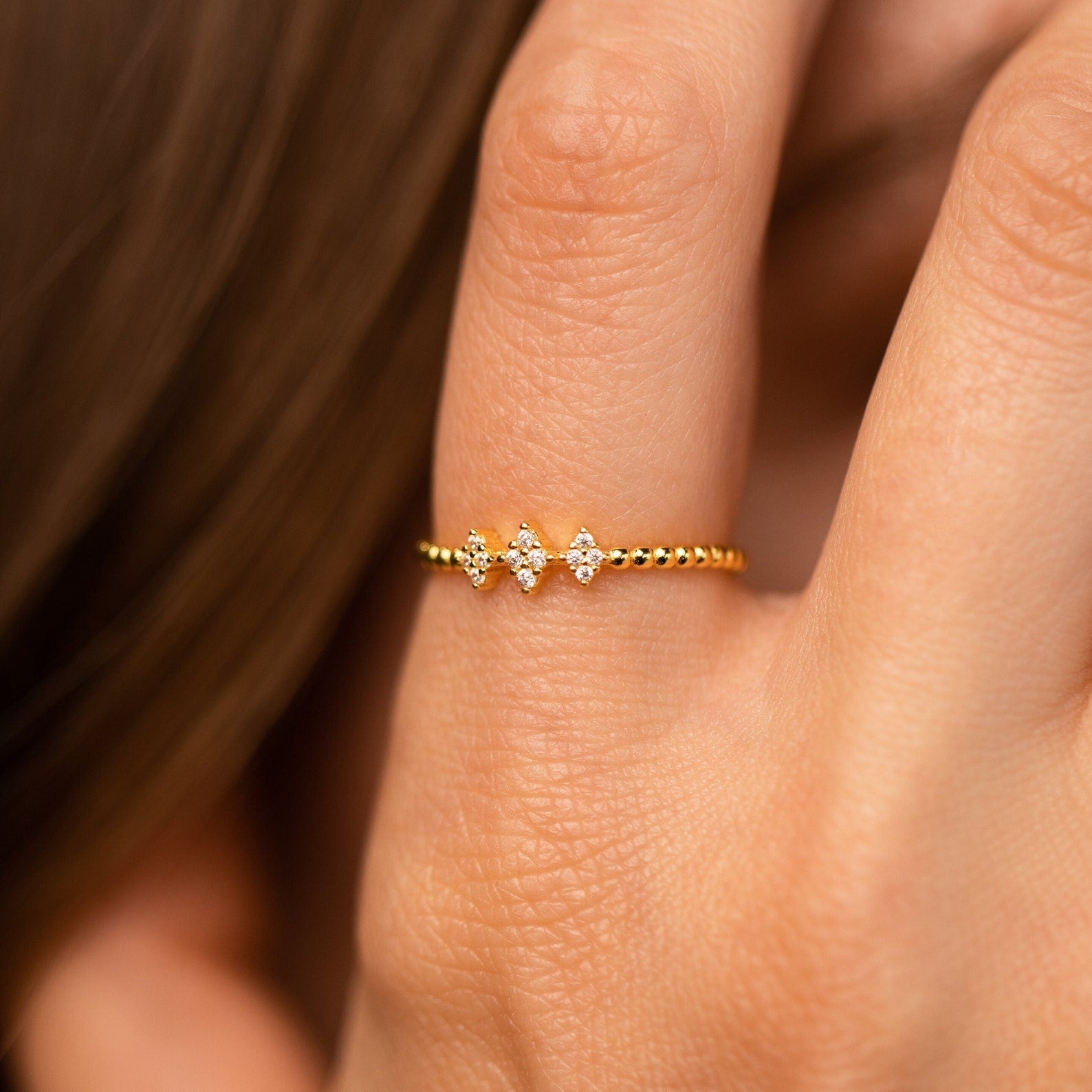 The Jasmine Beaded Diamond Ring features a gold beaded band with three sparkling stones, adding an elegant touch to any ring stack.