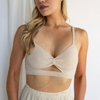 Woman wearing a beige bralette, cream skirt, and the Kara Body Chain—delicate gold jewelry perfect for summer—standing by a white curtain.