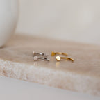 Tiny Circle & Triangle Huggies—one in silver, one in gold—displayed on beige marble. Perfect minimalist additions to your earring stack.