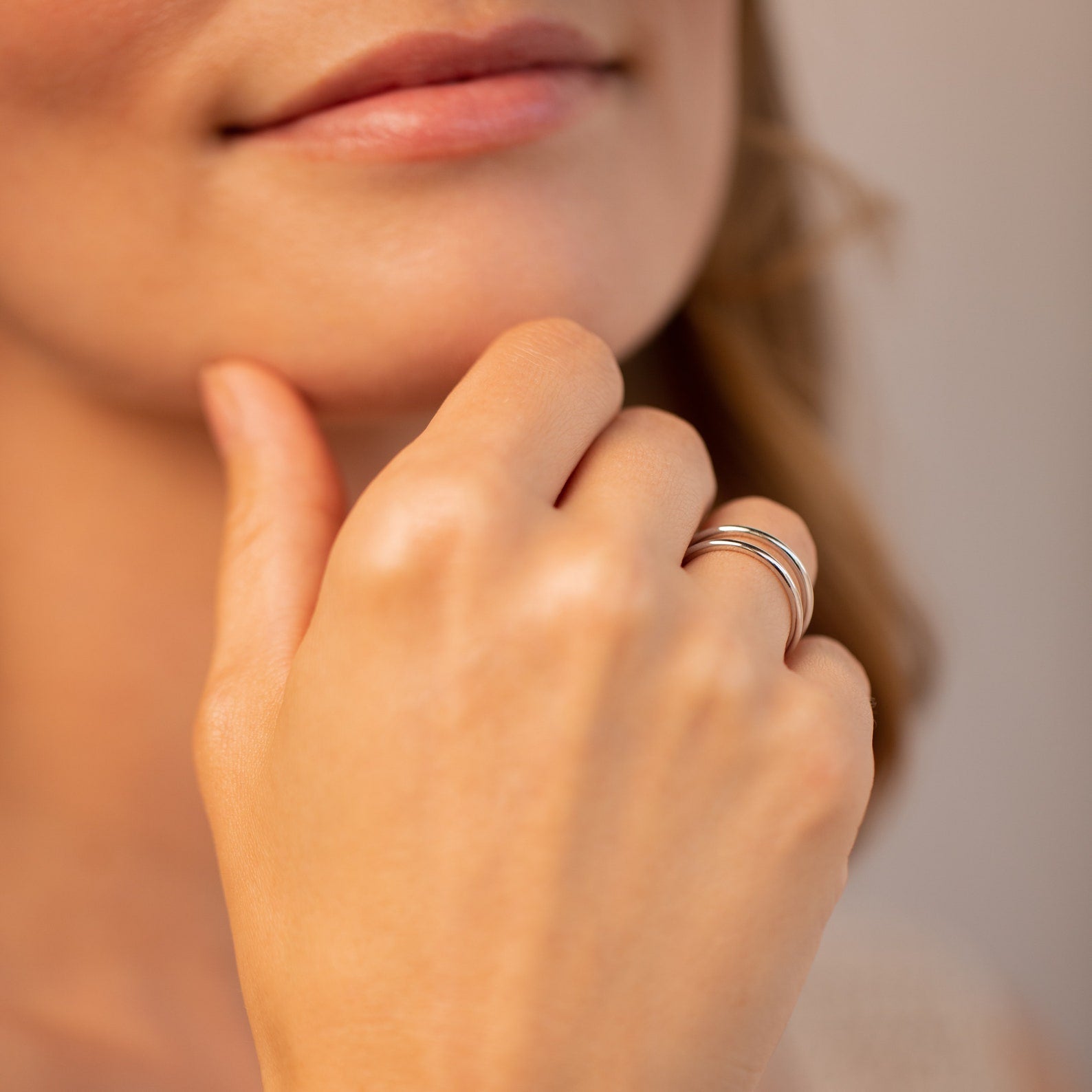 A woman's hand with the Everly Thin Duo Band ring touches her chin, accentuating her smooth skin and subtle smile.