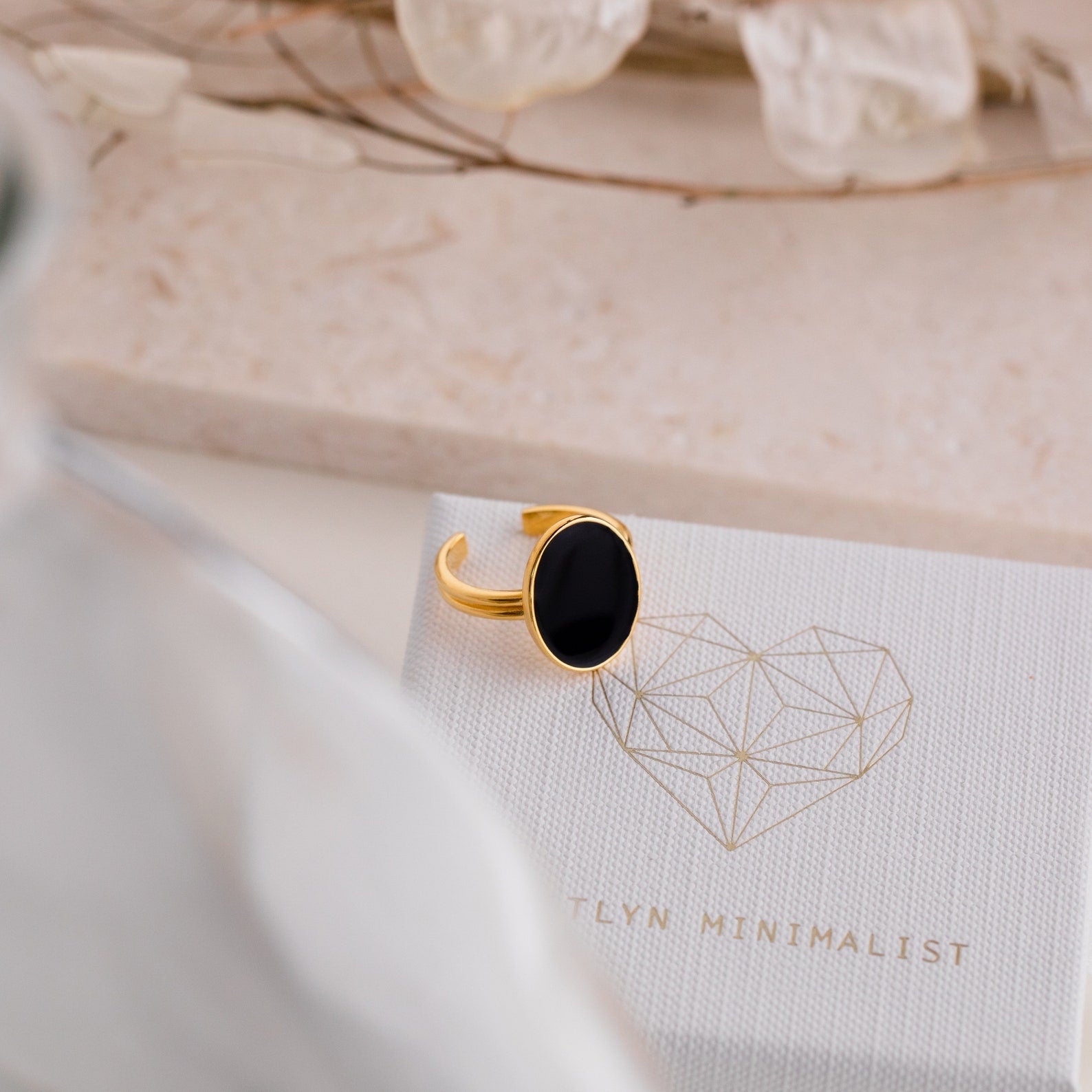 Midnight Hour Onyx Ring with adjustable band, featuring a black oval stone, displayed on a textured box with a geometric heart design.