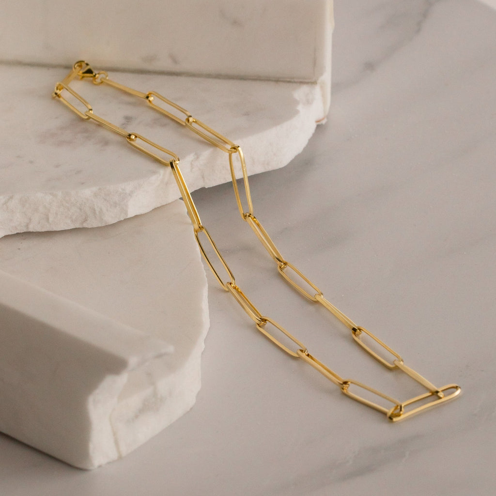 The Custom Link Chain Necklace, displayed on white marble slabs, makes a bold and stunning statement.