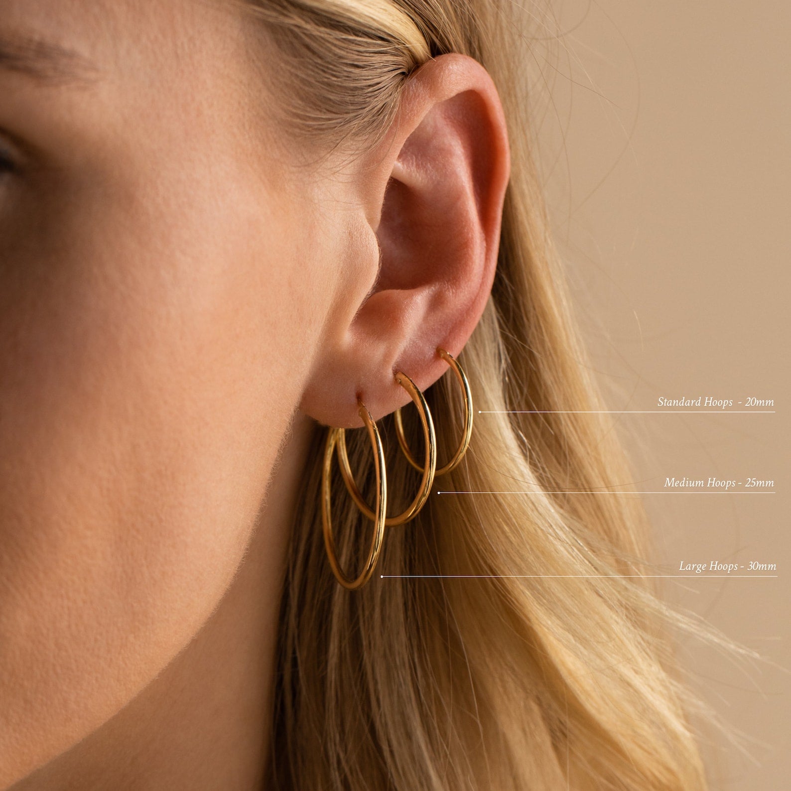 Close-up of a woman’s ear featuring three Endless Thin Hoops—standard, medium, and large—showcasing these timeless earrings as the perfect everyday accessory.