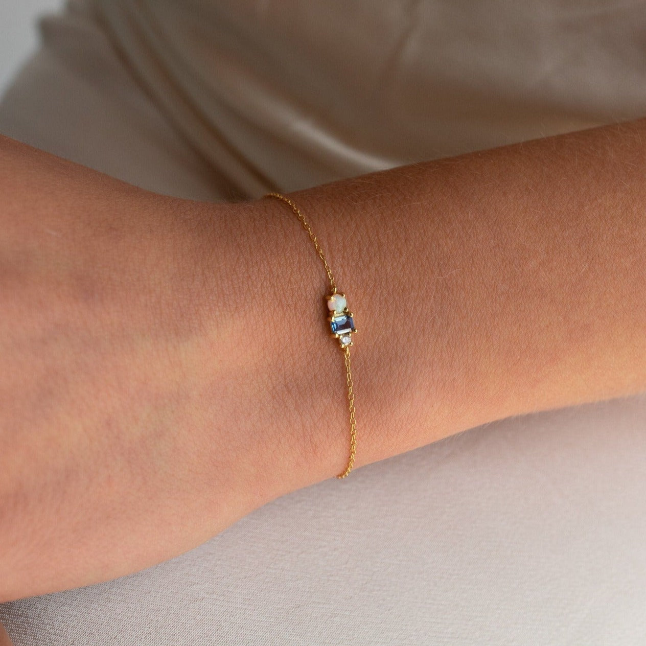 The Eloise Gemstone Bracelet, featuring a delicate chain and a small multicolored rectangular charm, rests gracefully on the wrist—perfect for fans of dainty jewelry.