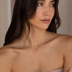 A woman with long brown hair, wearing a strapless top, looks off to the side while showcasing the Pave Linked Pendant Necklace.