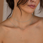 A woman with tousled hair and bare shoulders wears Beaded Station Necklaces in double-layered turquoise—perfect playful jewelry to elevate any style.