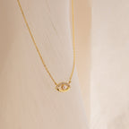 Amaryllis Pave Evil Eye Necklace in 18K Gold featuring a sparkling pendant, shown against a soft cream-colored fabric background.