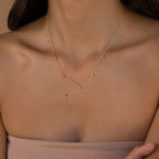 A woman in a strapless nude top wears the Marquise Station Necklace, featuring marquise-shaped diamonds and teardrop charms on a delicate chain.