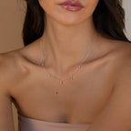 A woman wears the Marquise Station Necklace, a delicate silver chain featuring small teardrop diamond charms, paired with a strapless top.