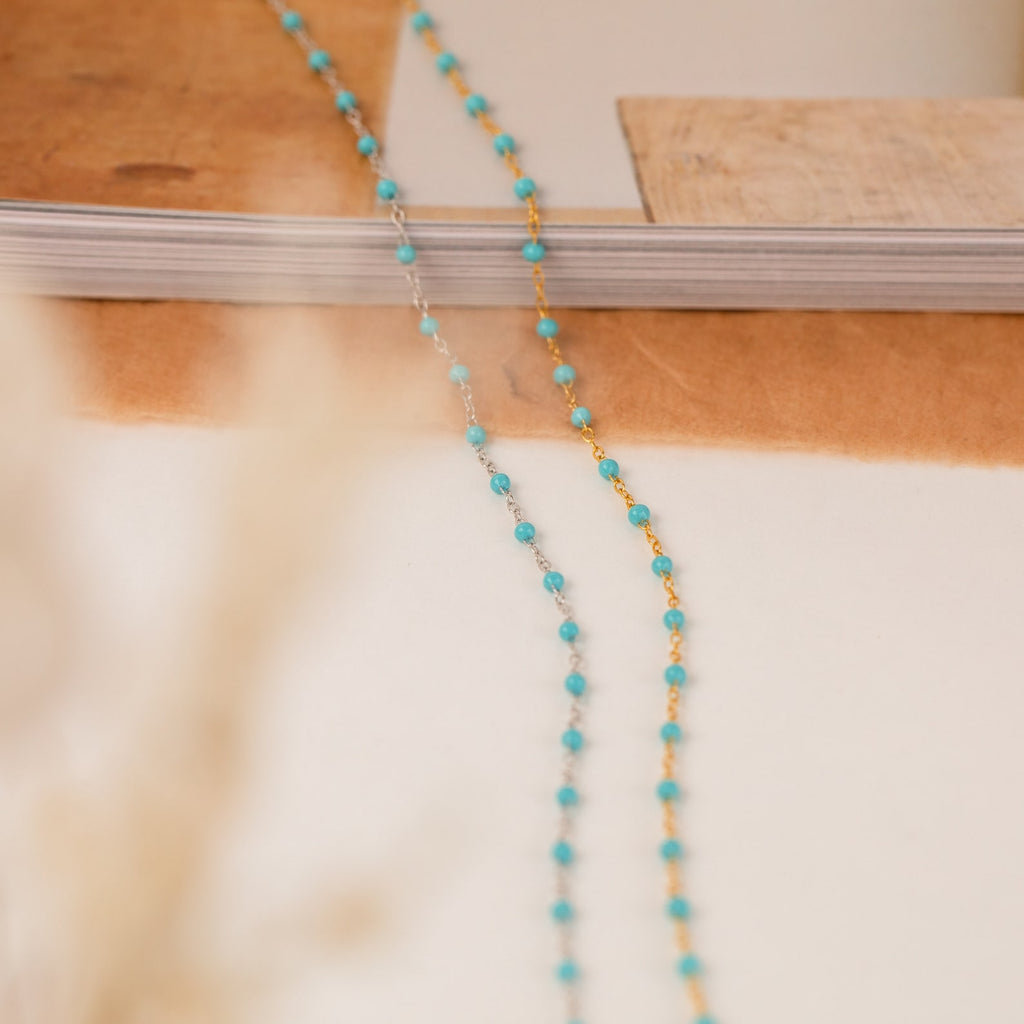 Beaded Station Necklaces in turquoise and gold are elegantly displayed on a neutral surface with a soft background.
