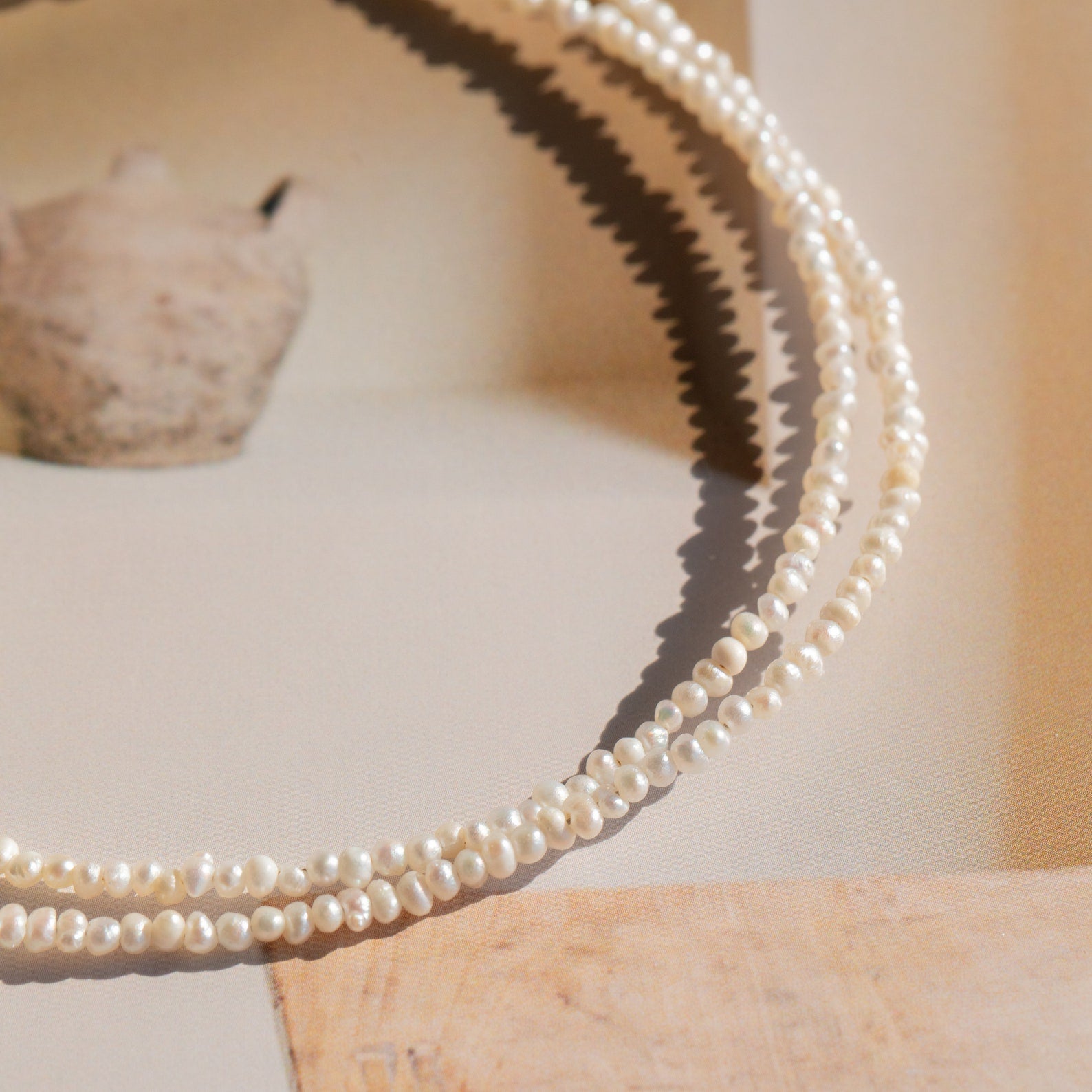 Close-up of the Brinley Pearl Anklet: fine metallic chain with small lustrous pearls spaced evenly, capturing the soft shine of each pearl.