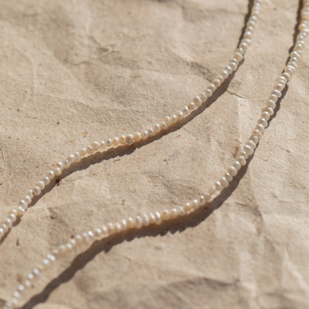 Detail shot of the Brinley Pearl Anklet draped against a neutral textured surface, highlighting the pearls’ smooth, luminous finish and elegant simplicity.