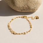 Close-up of the Magnolia Pearl Wrap Bracelet coiled in a circular shape, showcasing its dainty freshwater pearls and gold bead accents on a white background.