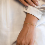 Hand resting gently on neutral-toned fabric while wearing the Magnolia Pearl Wrap Bracelet, styled as an everyday elegant accessory.