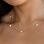 The Anna Pearl Station Necklace features evenly spaced white pearls on a gold chain, resting elegantly on the neck—perfect as a Mother’s Day or bridesmaid gift, shown close up against the skin.