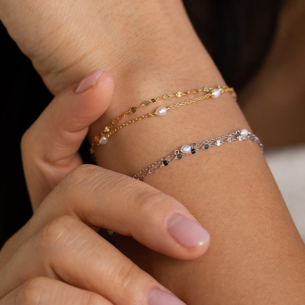Female wrist wearing the Magnolia Pearl Wrap Bracelet, highlighting its layered pearl strands and subtle gold and silver against warm-toned skin.