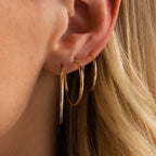A close-up of a woman's ear adorned with the Thin Hoops Set, showcasing these classic earrings as the perfect everyday accessory.