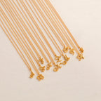 The Davina Letter Necklace features elegant gold cursive initial pendants, beautifully arranged on a light beige background—an ideal romantic gift for someone special.