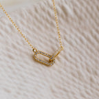 The Pave Linked Pendant Necklace features two interlocking, diamond-studded oval links on a gold chain—ideal for adding a touch of glamour to any outfit.