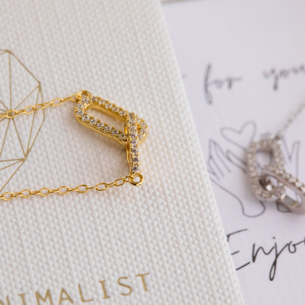 Pave Linked Pendant Necklace featuring a crystal-encrusted pendant displayed on a textured white card, showcasing glamorous elegance and sparkling allure.