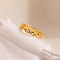 The Reese Link Ring, a minimalist gold chain ring, is displayed on a soft white fabric pouch against a neutral background.