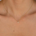 Gold chain necklace with a small butterfly-shaped pendant adorned with clear gemstones, worn with a strapless nude top.