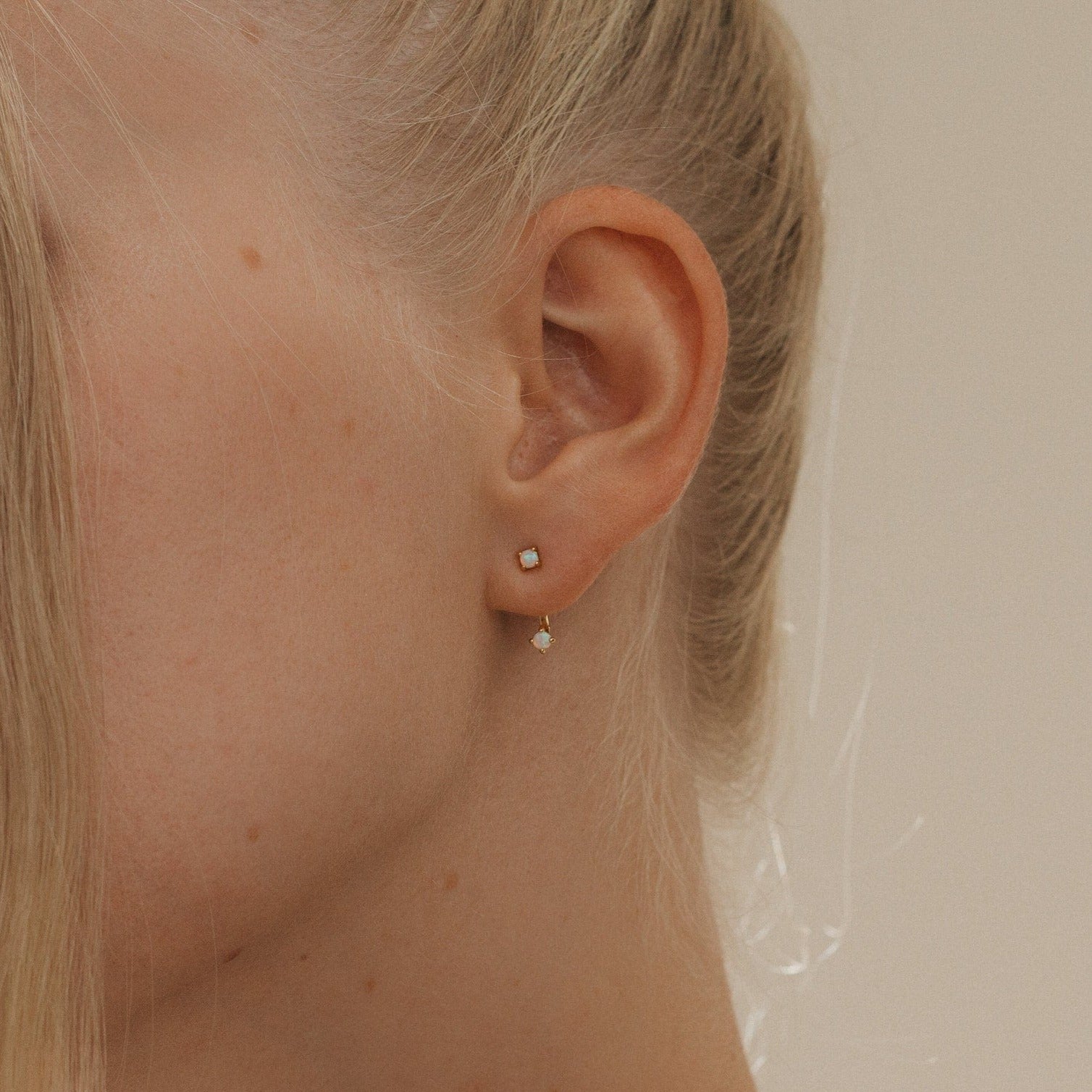 Close-up of a woman's ear wearing Opal Ear Jackets, her blonde hair pulled back to showcase the minimalist gold design.
