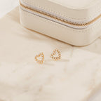 Pearl Heart Studs featuring gold heart-shaped designs with dainty beaded charms are displayed next to a cream jewelry box on a beige marble surface, ideal for vintage jewelry enthusiasts.