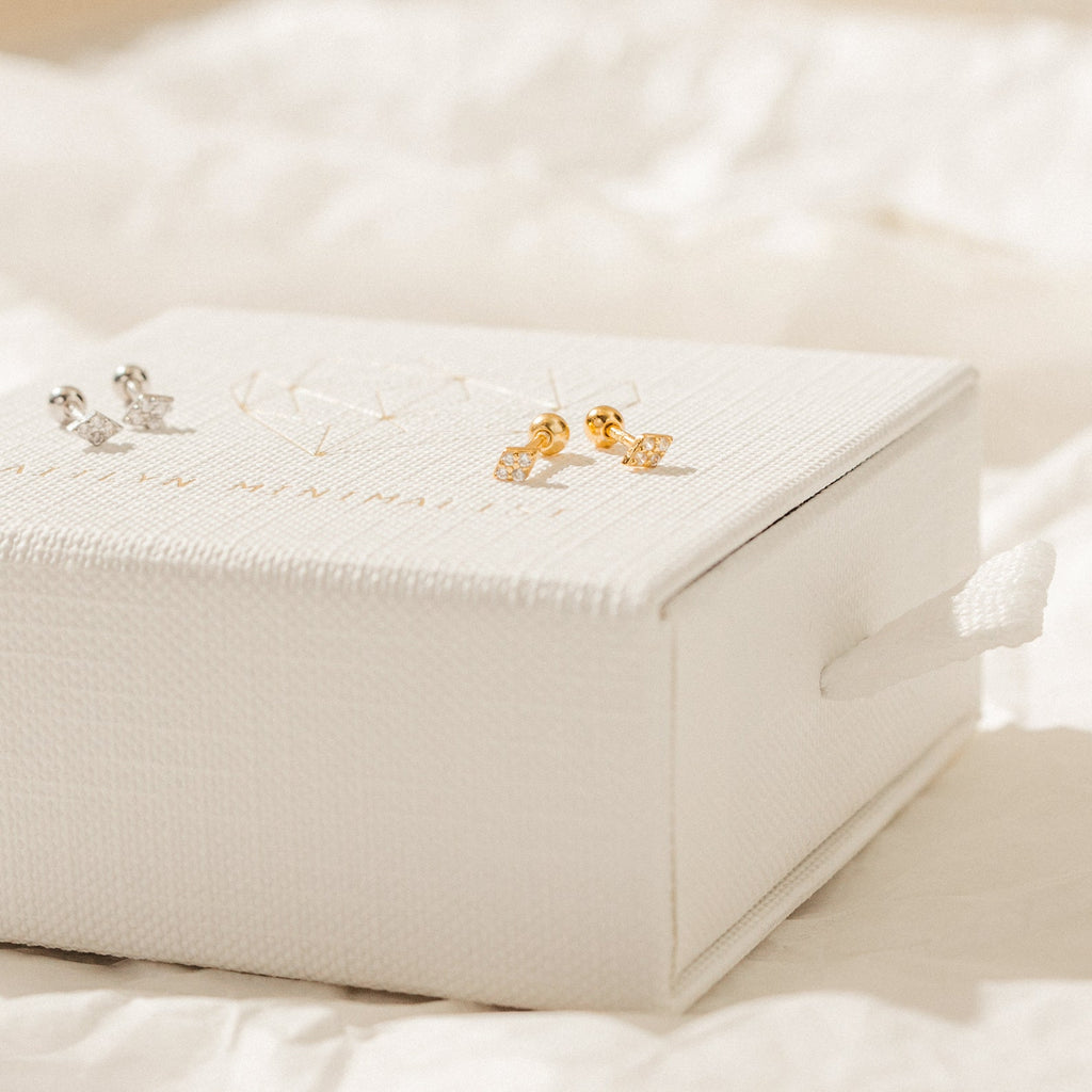 The Jocelyn Diamond Studs in Sterling Silver—perfect for everyday earring stacks—are elegantly displayed on a textured white jewelry box.