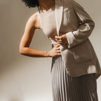 A person wearing a beige blazer, ribbed tank top, Venus Diamond Station Bracelet, and pleated skirt poses against a neutral background.
