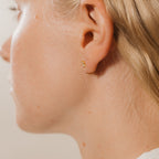 Close-up of a person's ear wearing Saylor III Huggies—one delicate hoop in the lobe and another in the helix—ideal for effortless everyday style.