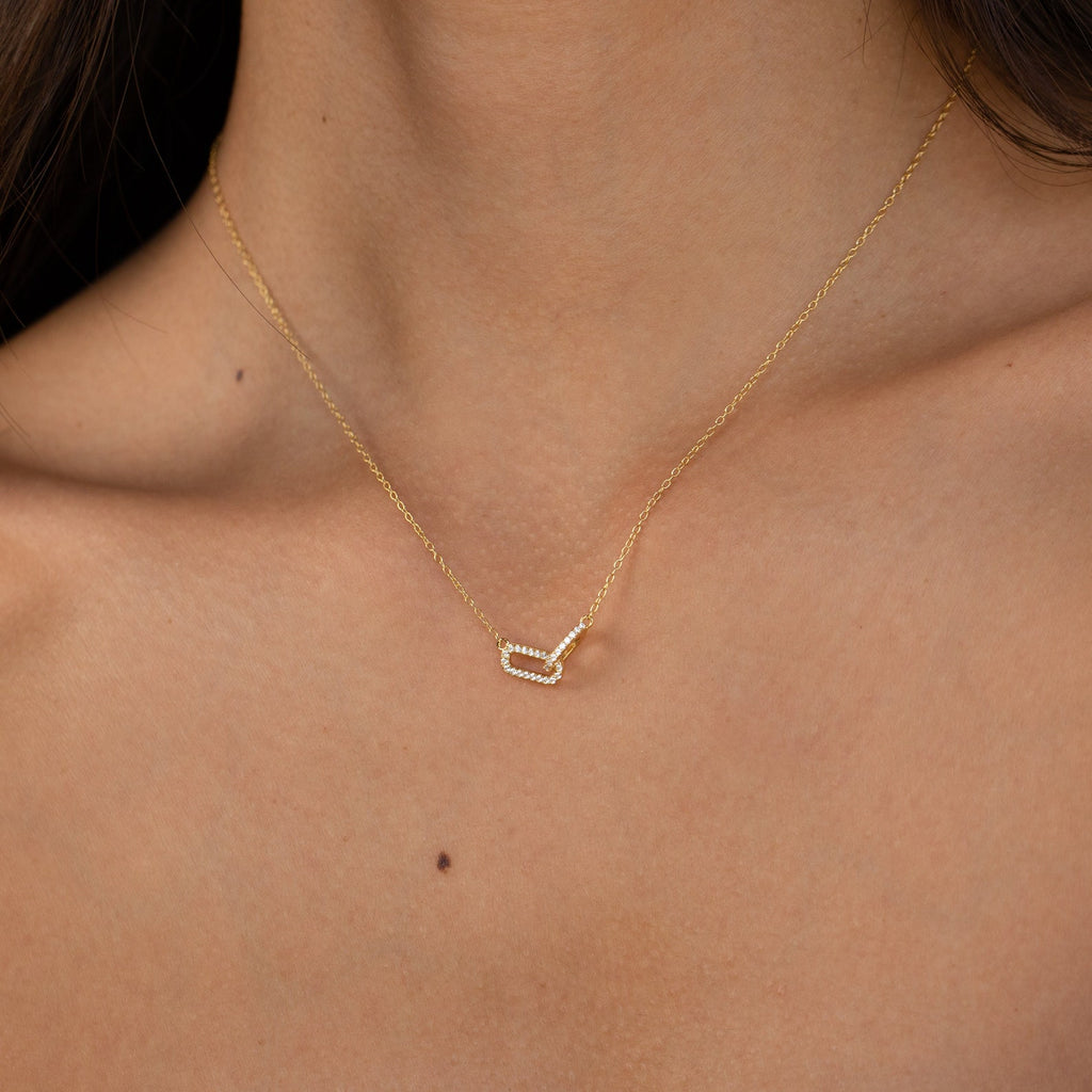The Pave Linked Pendant Necklace is a glamorous gold link charm necklace featuring a small geometric pendant that rests elegantly against the skin.