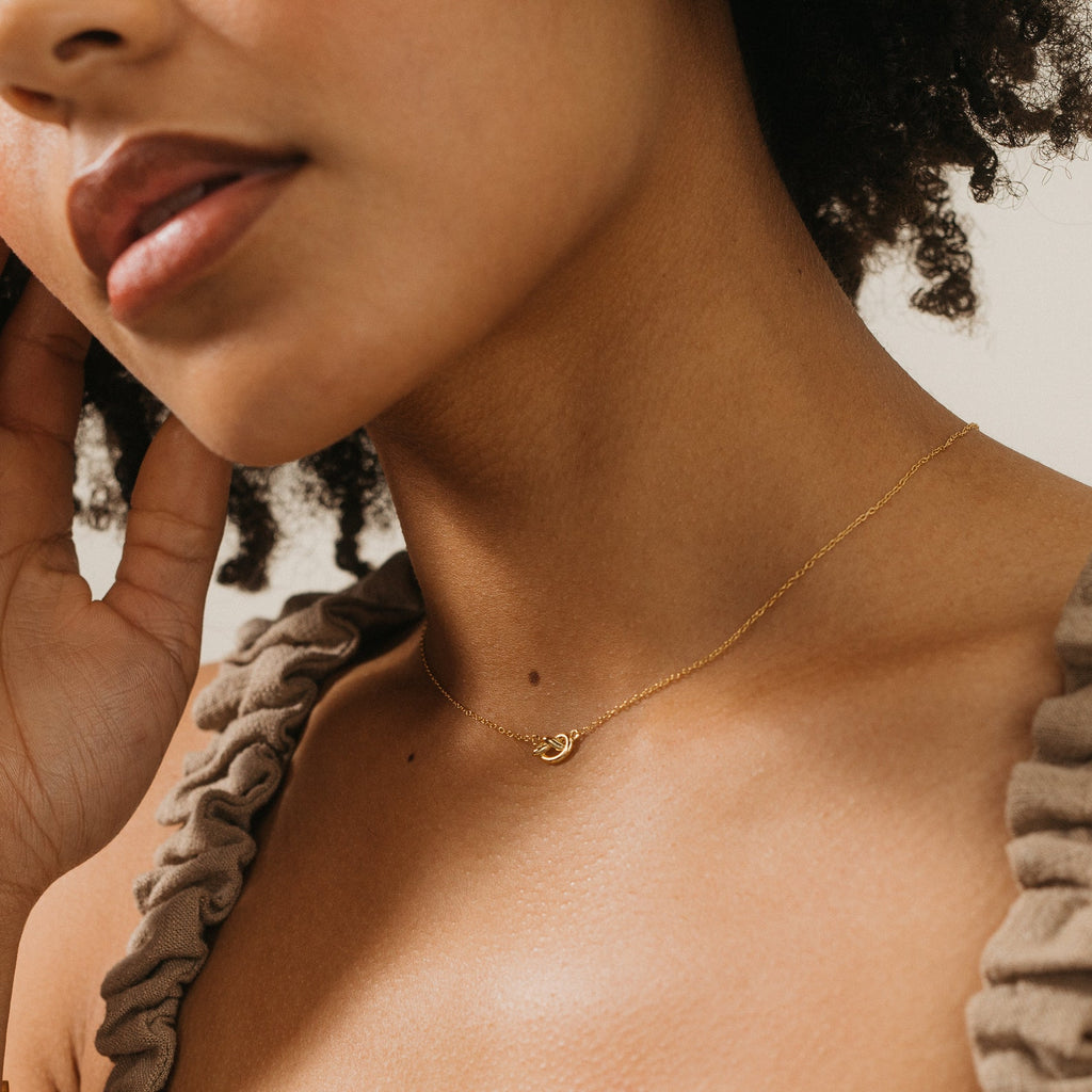 Close-up of a woman wearing the Love Knot Necklace, a delicate gold piece symbolizing unity—perfect as a wedding gift.