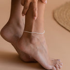 Styled view of a foot with the anklet worn just above the ankle, paired with other minimal jewelry layers, evoking a boho-chic summer aesthetic.